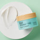 Eye Cream product with a swipe of white cream on a round surface, on a mint green background