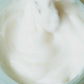 Close-up of a hand stirring a white creamy mixture in a container