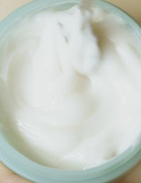 Close-up of a hand stirring a white creamy mixture in a container