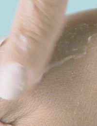 Close-up of a finger rubbing cream onto skin
